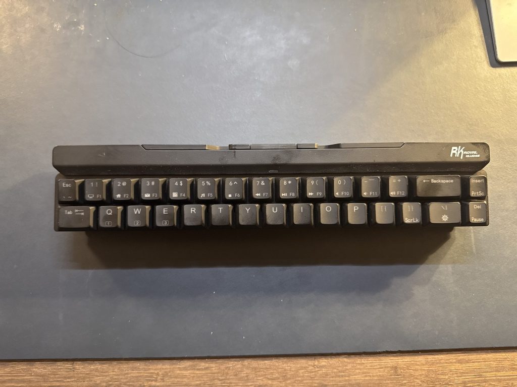 Top view of a Royal Kluge mechanical keyboard with low-profile keys, placed on a dark surface.